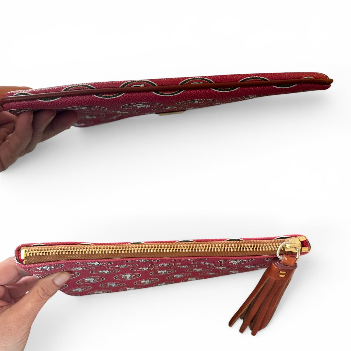Red patterned clutch with gold zipper and tassel held by a hand showing the top and bottom on a white background
