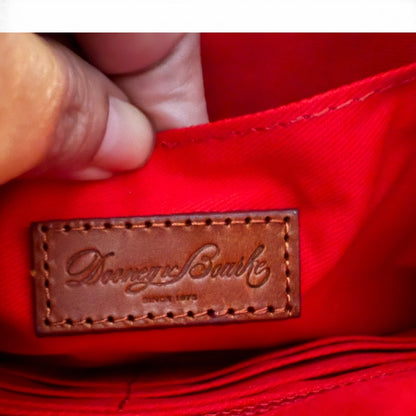 Close-up of a brown leather label on red fabric, featuring a brand name.