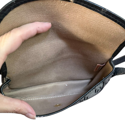 Close-up of a hand holding open a black handbag with a beige interior.