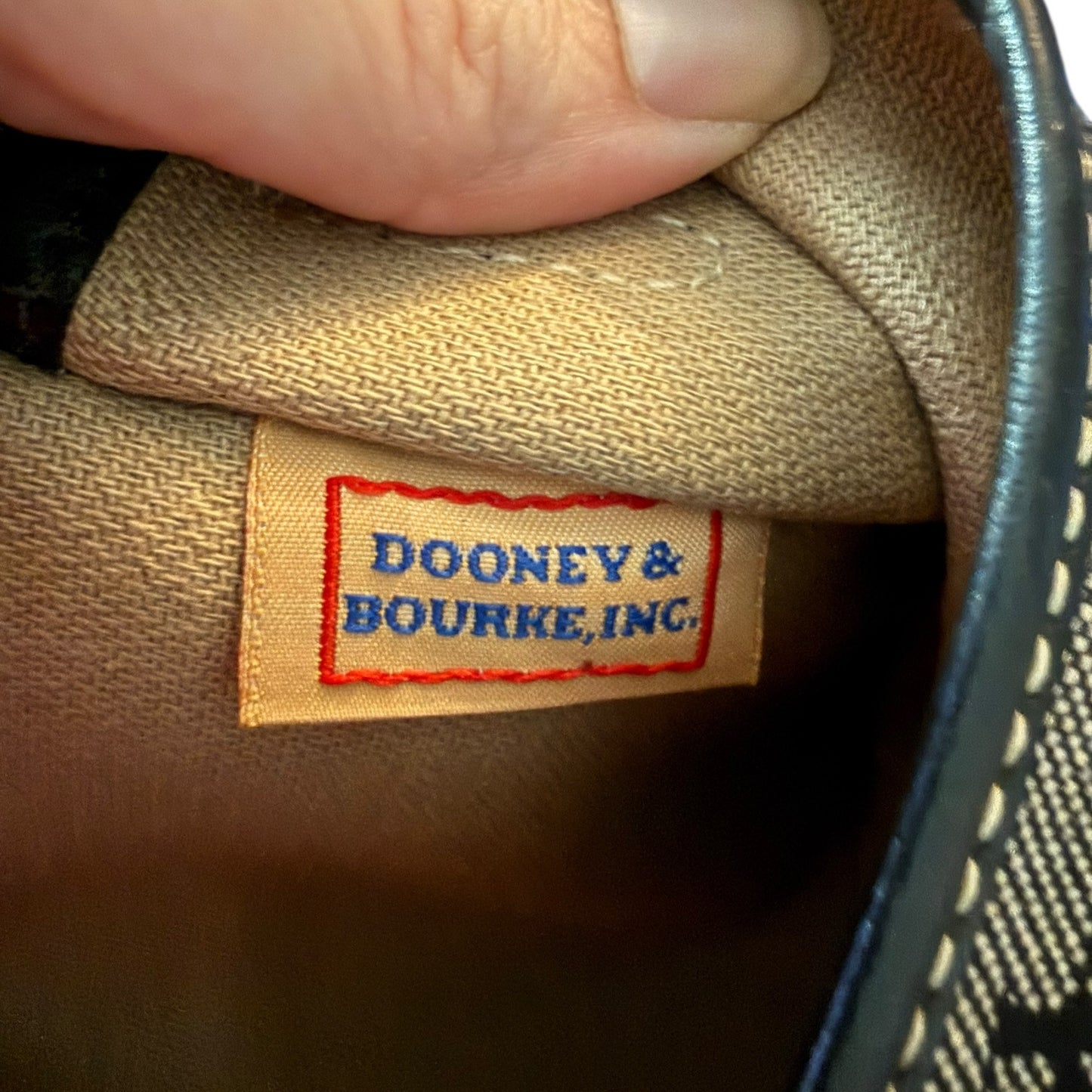 Dooney & Bourke label on a brown fabric surface