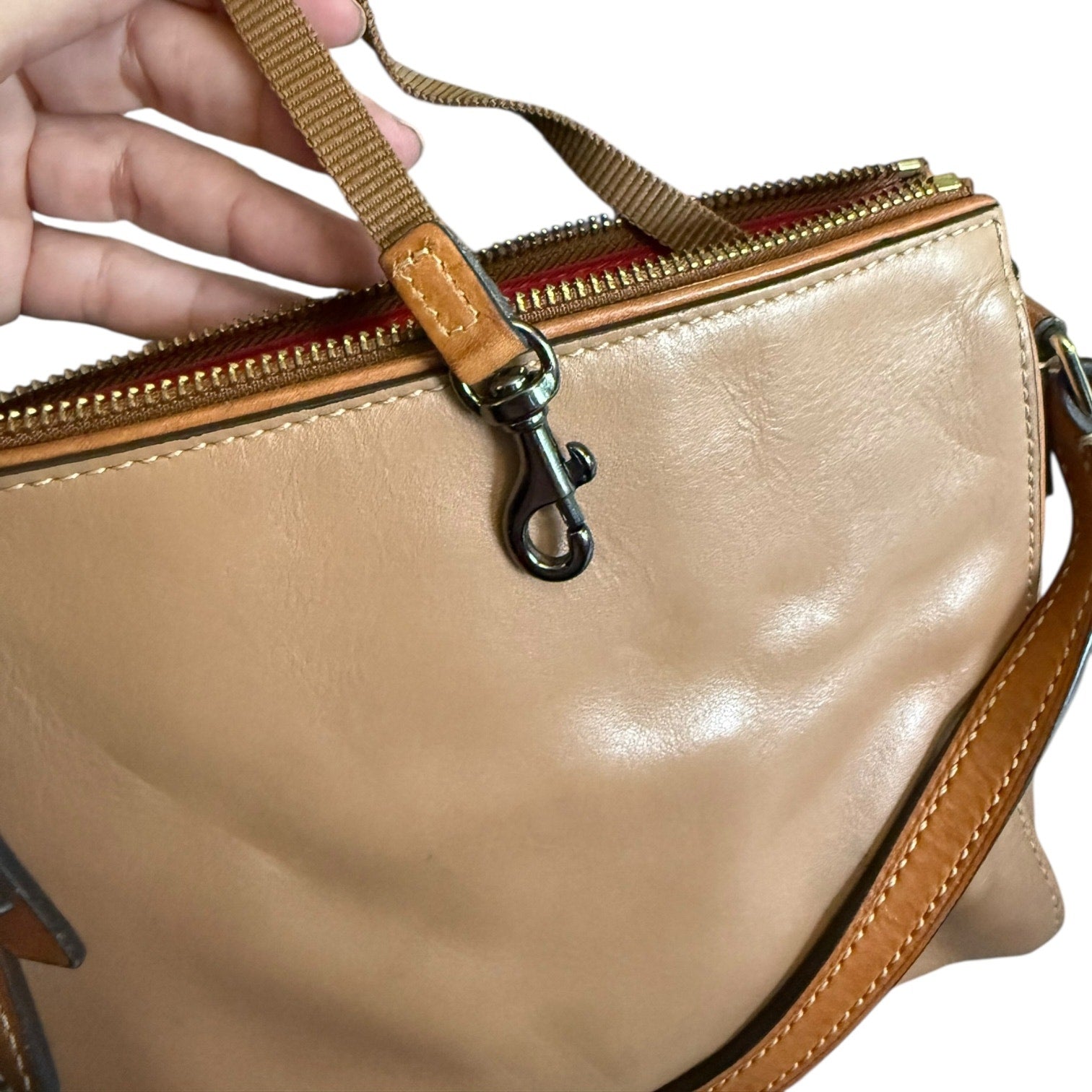 Brown handbag with brown strap and zipper on a white background