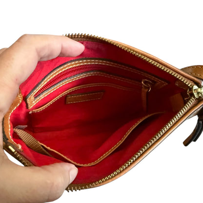 Hand holding brown purse open with a red interior with gold zipper on a white background