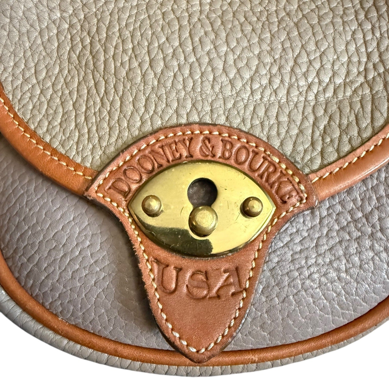 Close-up of a leather product with a gold emblem and 'Dooney & Bourke USA' branding.