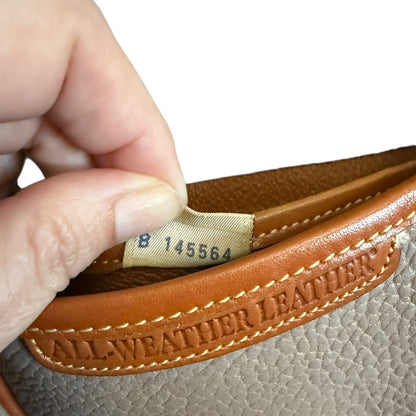 Close-up of a hand holding a tag with serial number and 'All-Weather Leather' text.