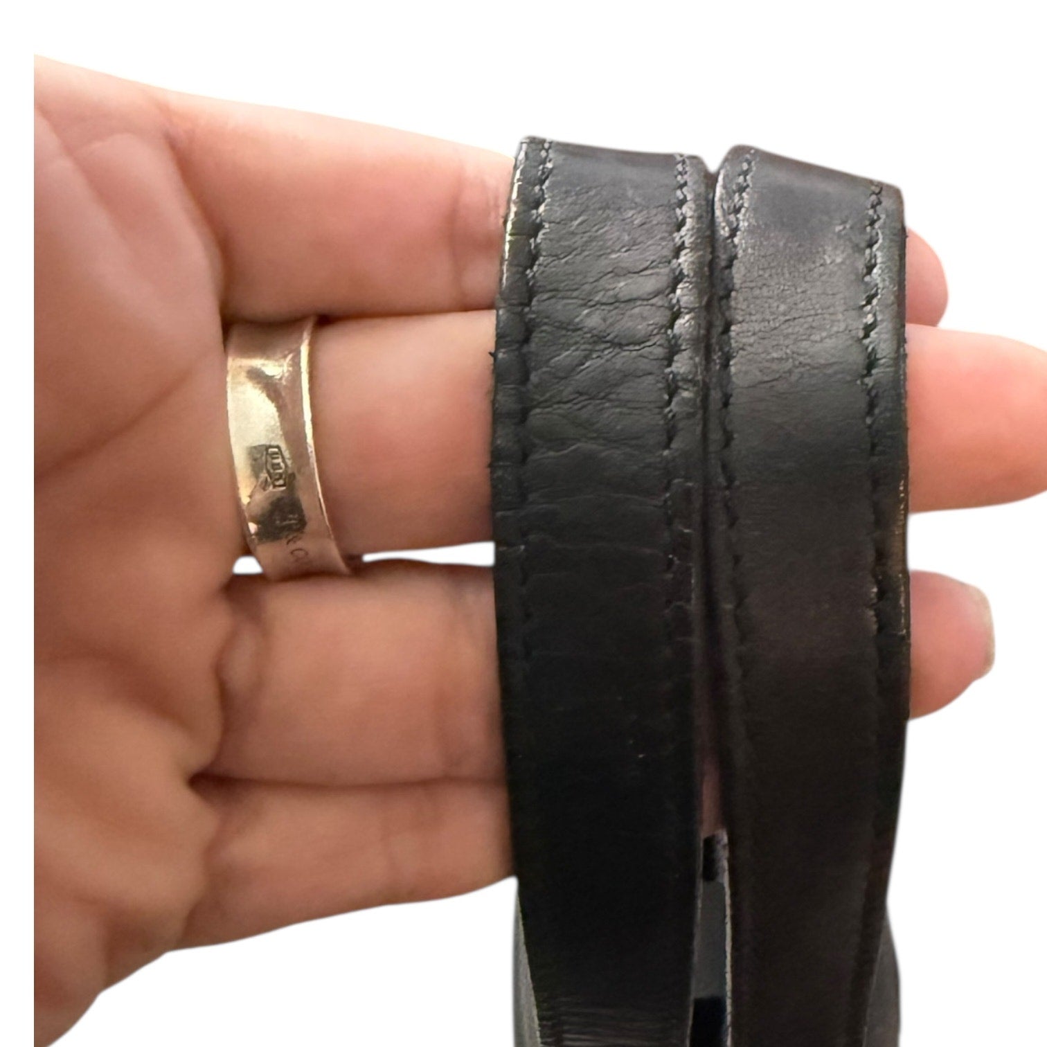 hand holding leather handbag straps  on a white background