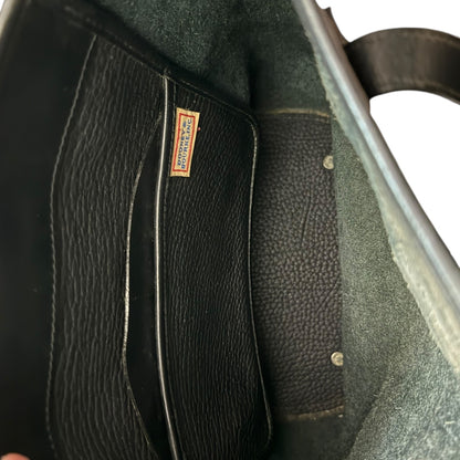Close-up of a black leather bag interior with a visible brand label on a white background