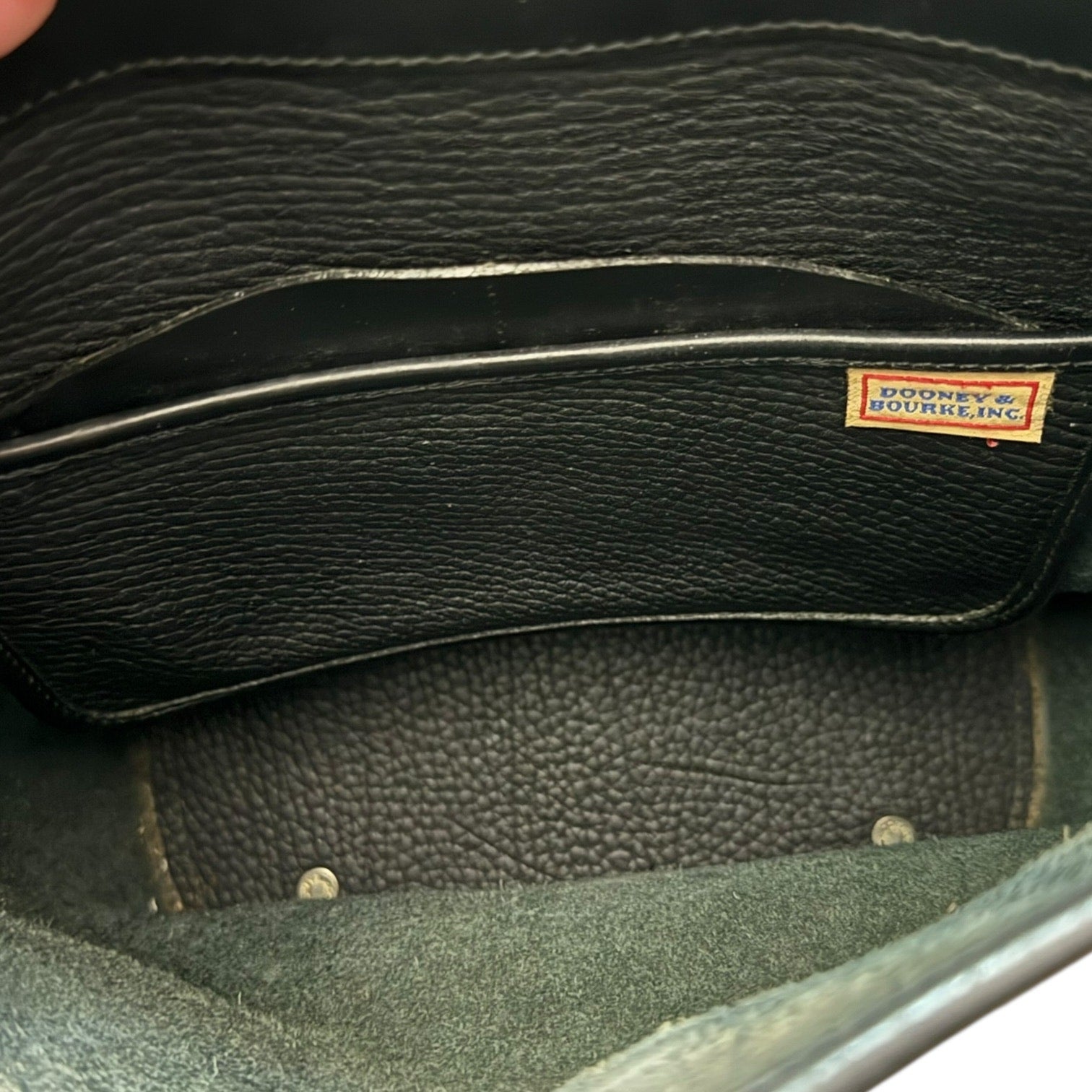 Close-up of a black leather interior pockets bag with a visible brand label.