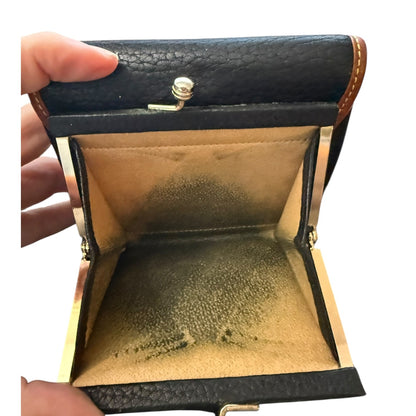 Open black leather wallet with gold interior, held by a hand.