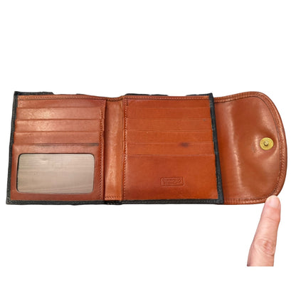 Brown leather wallet held open by a hand on a white background