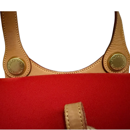 Red bag with brown leather handles and gold hardware on a white background