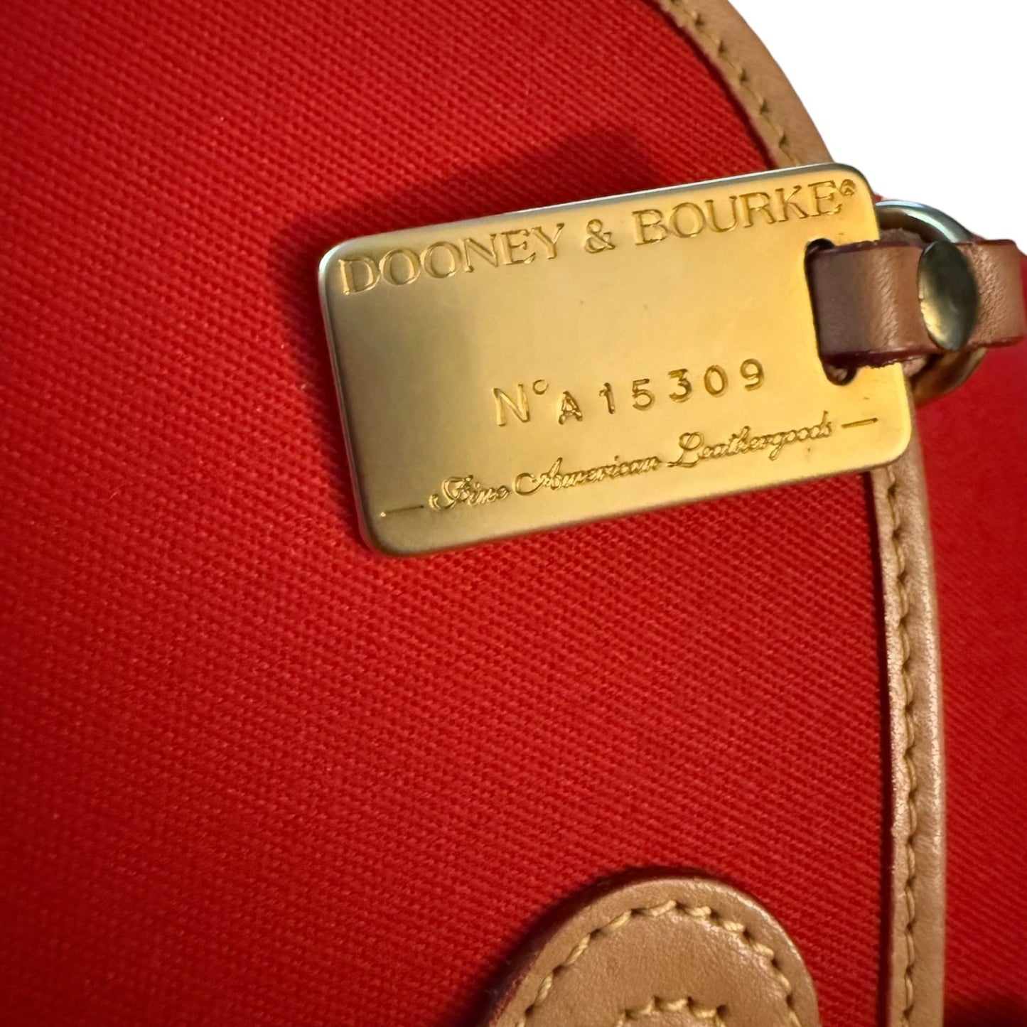 Dooney & Bourke luggage tag on a red purse background