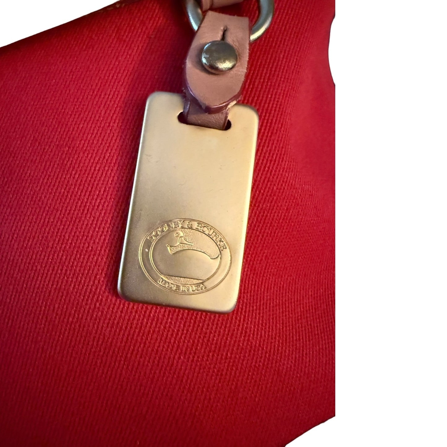 Brass tag with a duck logo on a red background