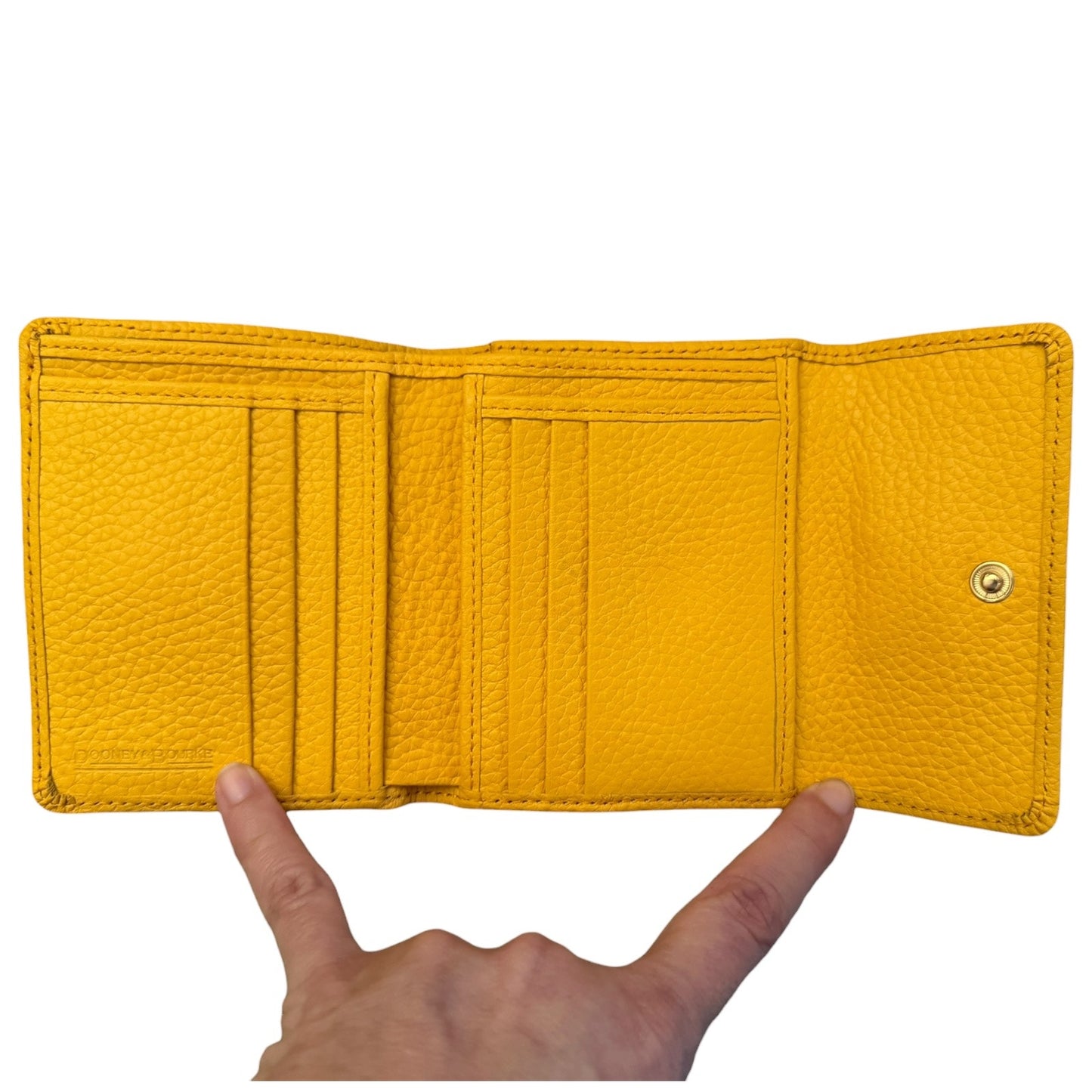 A yellow textured leather bifold wallet shown open, held by a hand to demonstrate its size, against a plain white background.