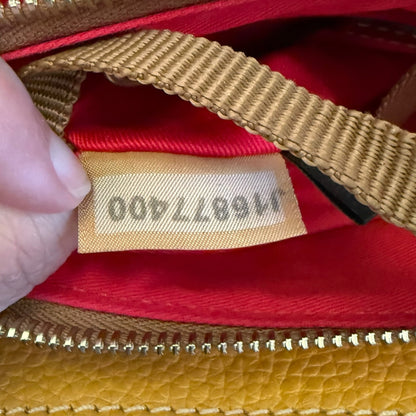Close-up of a hand holding open purse with red interior and a beige size with printed numbers.