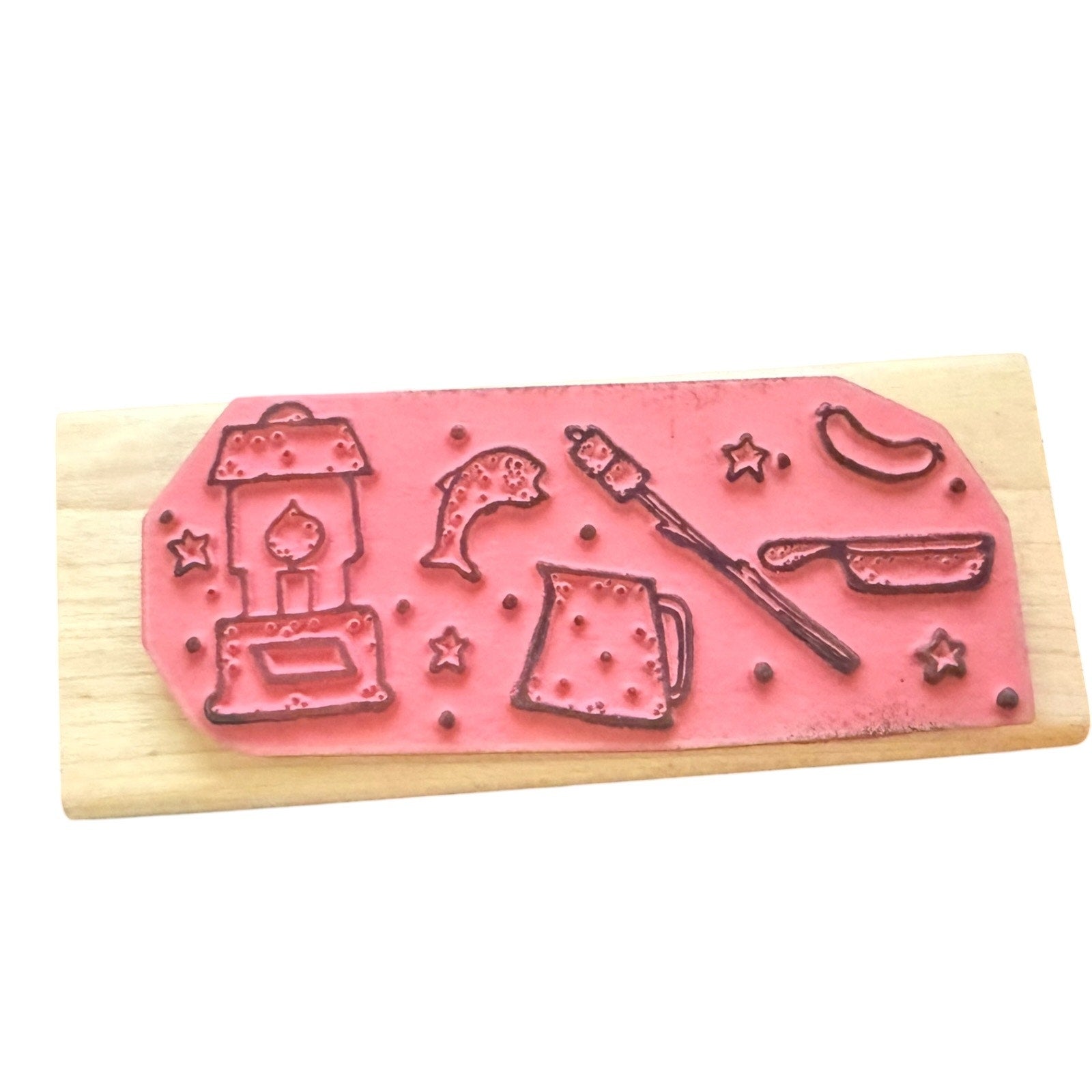 Pink stamp with various designs on a wooden block against a white background