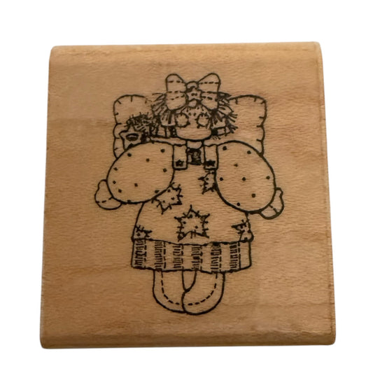 A square wooden stamp block featuring a black illustration of a character wearing a bow, hat, and dress with star details, shown on a plain white background.
