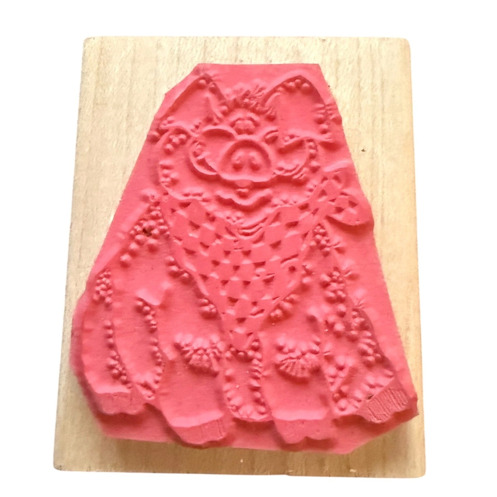 A pink rubber stamp , mounted on a light-colored wooden block against a white background.