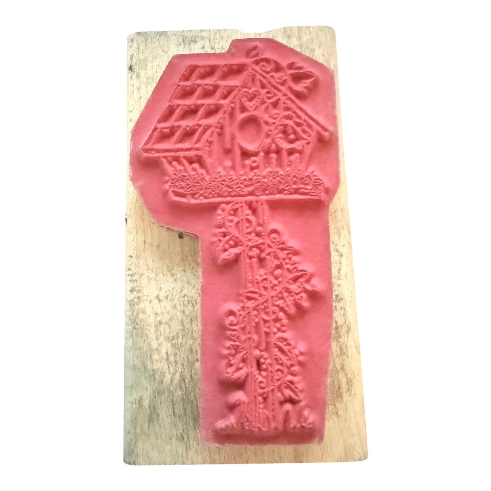 A pink rubber stamp featuring a treehouse design, mounted on a rectangular light-colored wooden block against a plain white background.