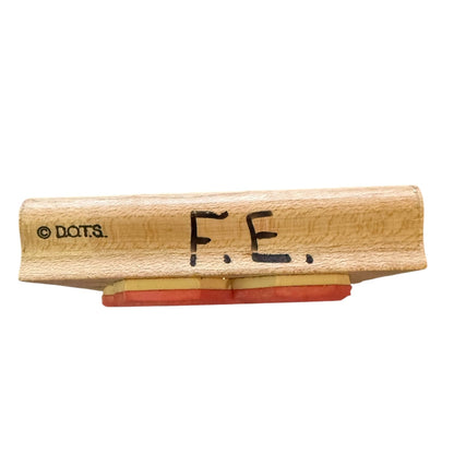 Wooden stamp with 'F.E.' text on a white background