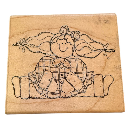 A square wooden rubber stamp block featuring a black line-art illustration of a smiling girl with long pigtails and a plaid dress, shown on a plain white background.