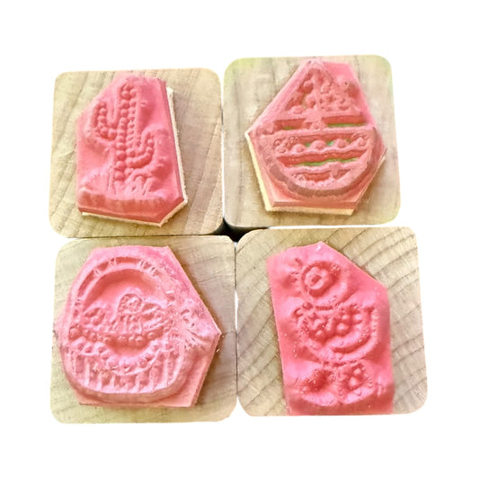 Four pink stamps with embossed designs on wooden blocks.