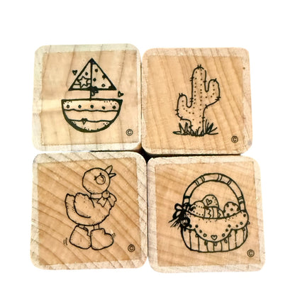 Four wooden stamps with engraved designs of a sailboat, cactus, duck, and basket on a white background.