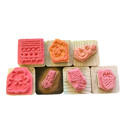 Set of wooden stamps with pink and brown designs on a white background