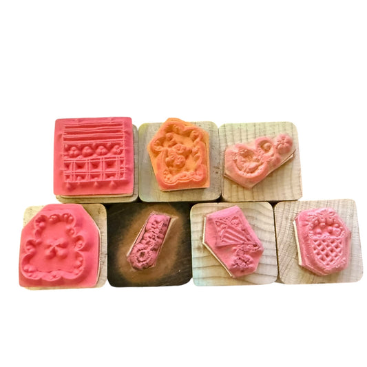 Set of wooden stamps with pink and brown designs on a white background