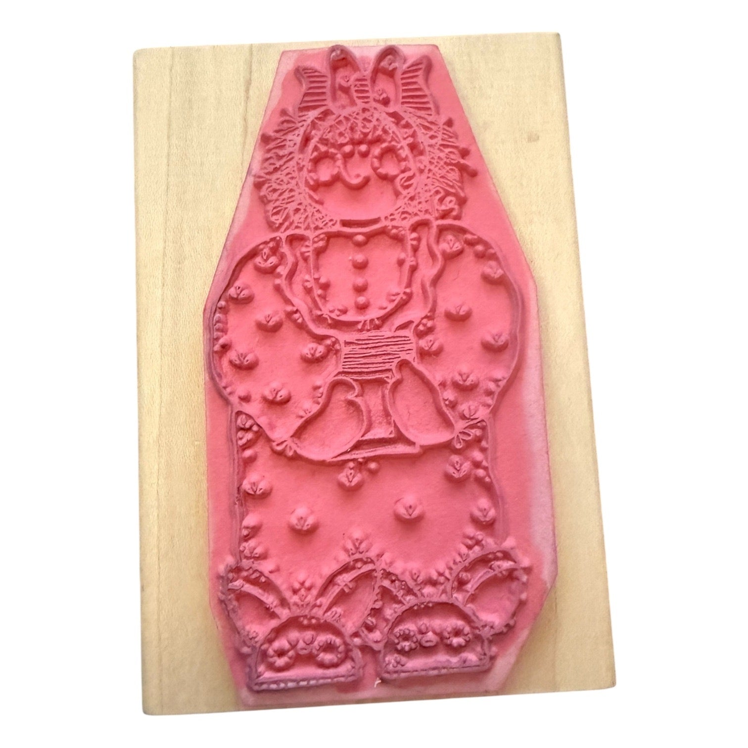 A pink rubber stamp mounted on a light-colored wooden block against a plain white background.