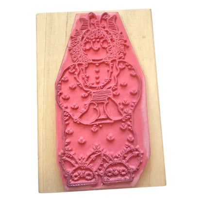 A pink rubber stamp mounted on a light-colored wooden block against a plain white background.