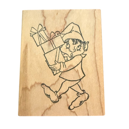 Wooden stamp with a design of an elf holding a gift box on a wooden background