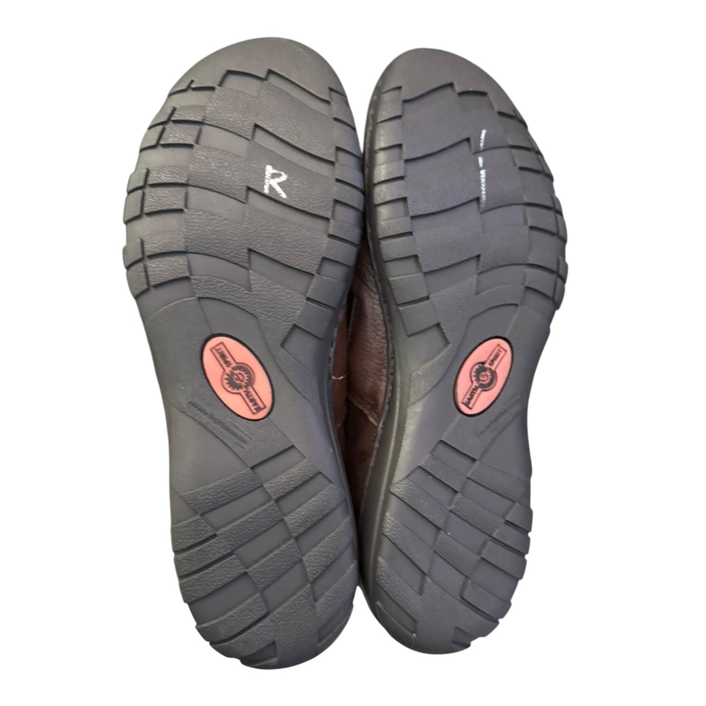 Close-up of a pair of shoes with tread pattern and brand logo on a white background