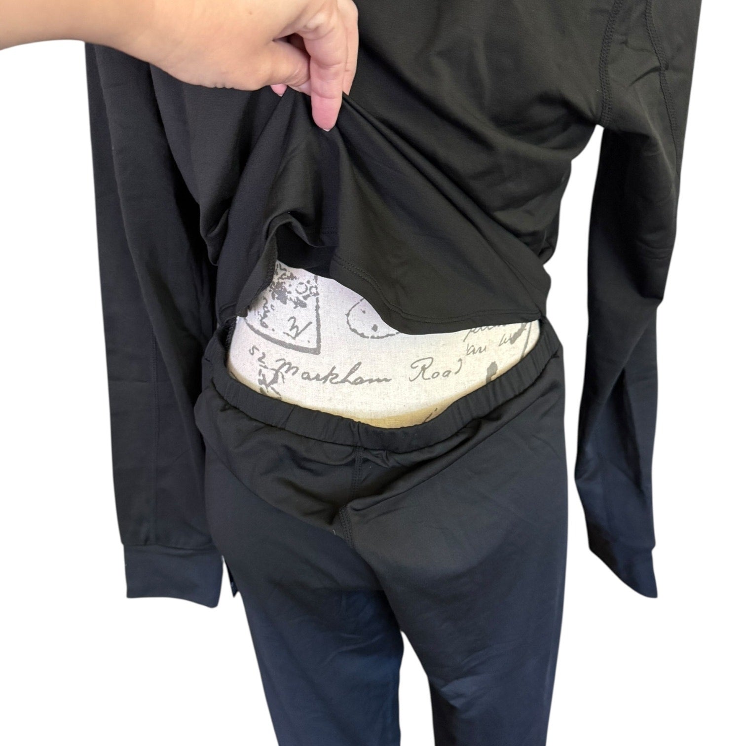 A close-up of back opening on a jumpsuit held open by a hand .