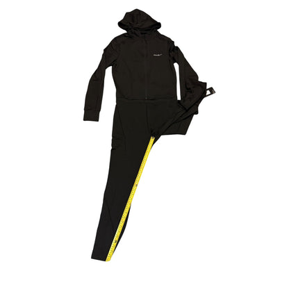 A black jumpsuit laid flat on a white background, featuring a zip-up hoodie with a small white logo on the chest and matching black pants with a yellow measuring tape running down the side.