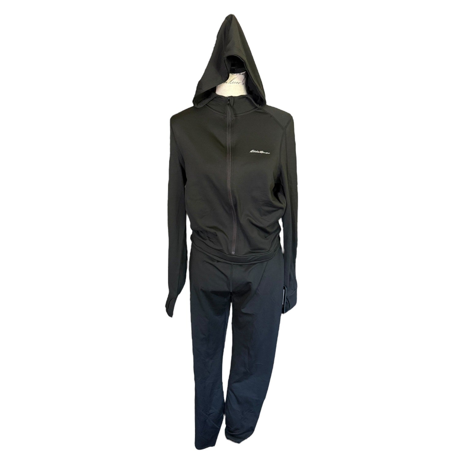 A black athletic jumpsuit consisting of a zip-up hooded jacket and matching pants, displayed on a mannequin against a plain white background.