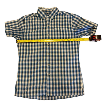 Blue and white shirt with a yellow measuring tape laying pit to pit on a white background
