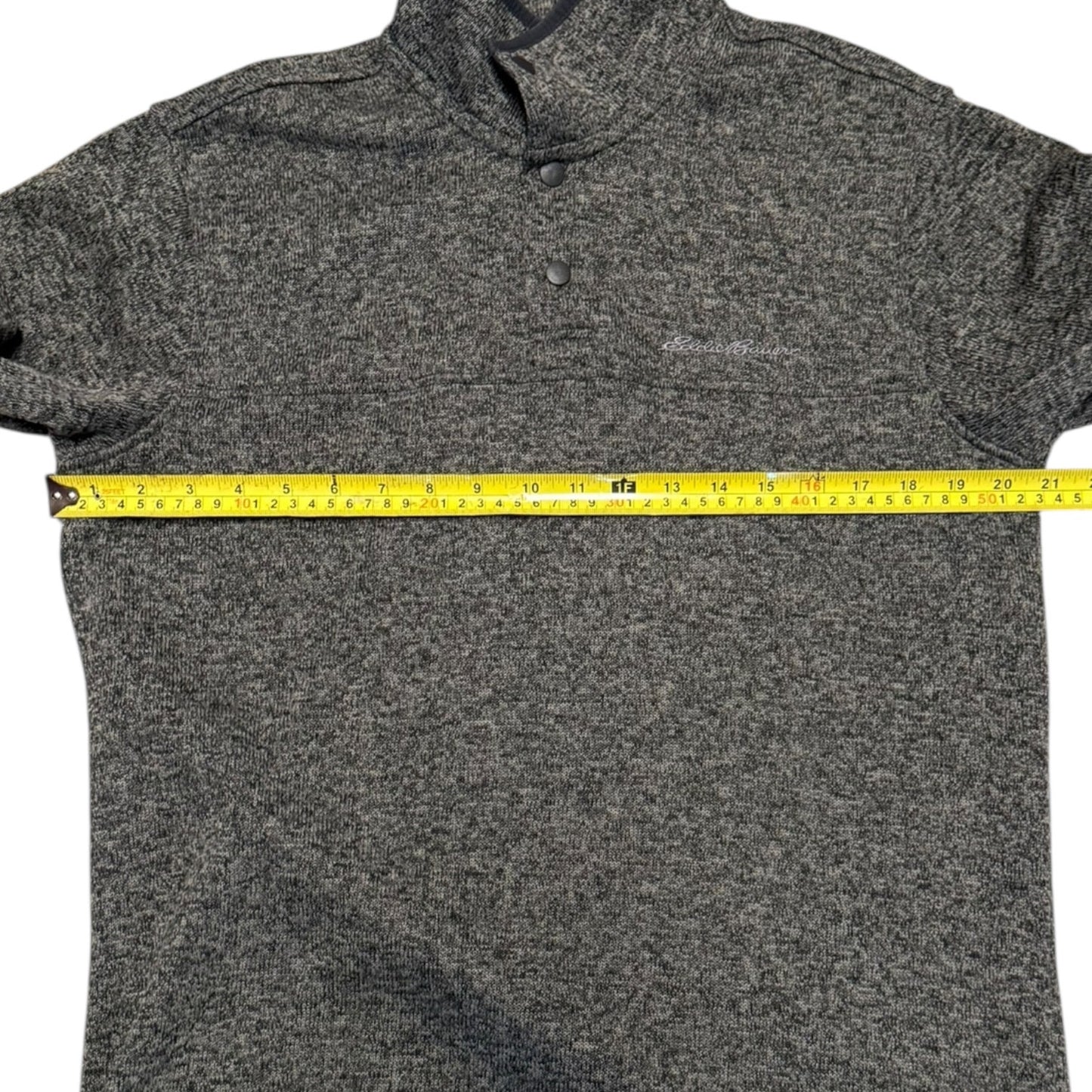 Gray sweater with a measuring tape across it on a white background