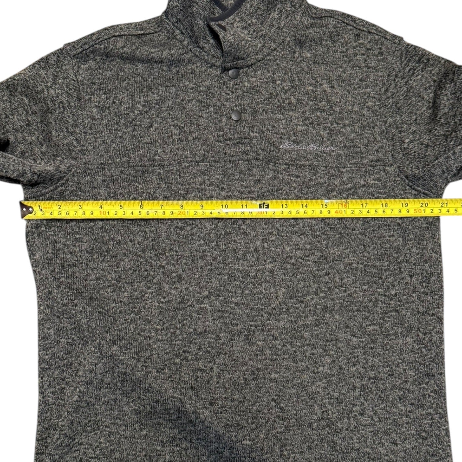 Gray sweater with a measuring tape across it on a white background