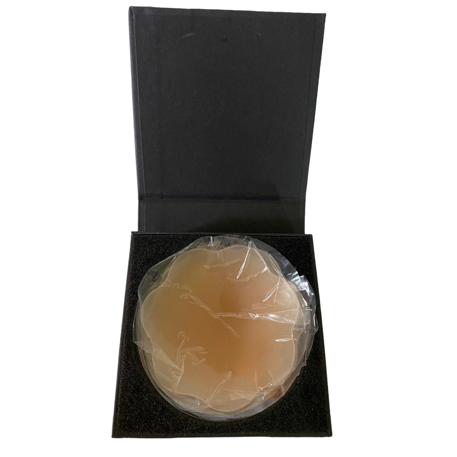 A silicone stick on bra cup wrapped in clear plastic, displayed inside an open black presentation box on a white background.