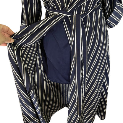 A close-up of a navy blue dress with white and blue diagonal stripes, featuring a hand holding open the front to reveal a solid navy blue lining.