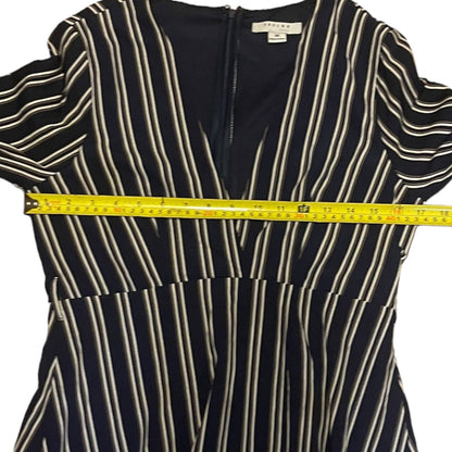 A short-sleeve striped dress with a front zipper, featuring vertical stripes on a white background, shown with a yellow tape measure across the chest.
