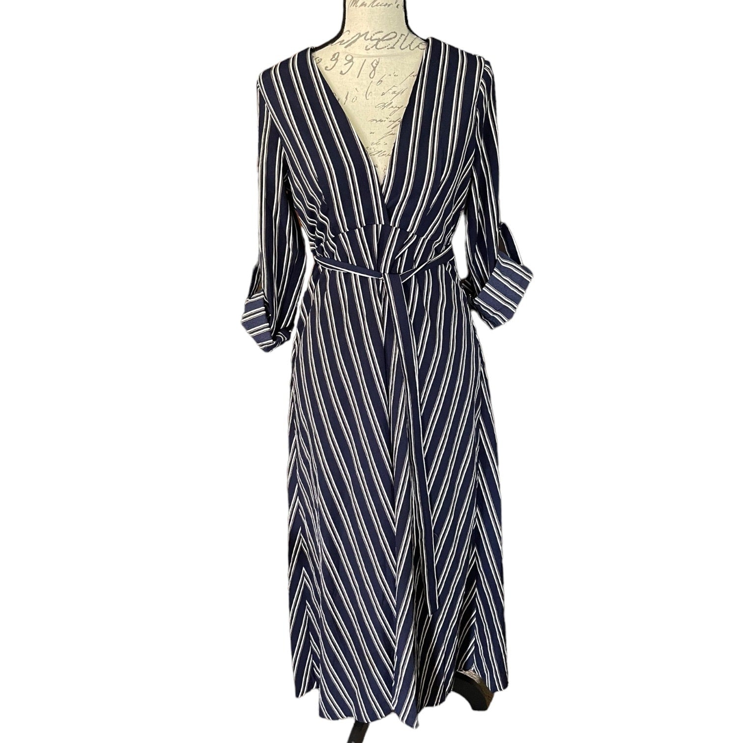 A navy blue and white striped wrap dress with three-quarter sleeves and a tie waist, displayed on a mannequin torso against a plain white background.
