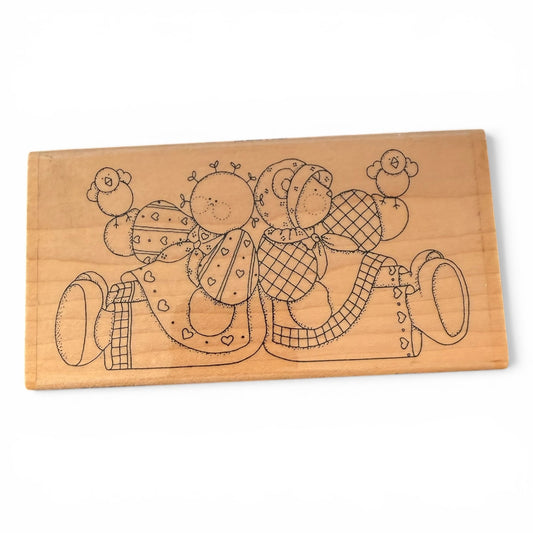 Wood stamp with engraved design of two teddy bears holding birds on a white background