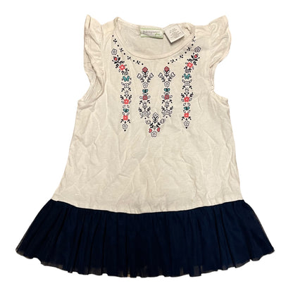 A girls' sleeveless top with ruffled cap sleeves, an white body, and colorful floral around the neckline, finished with a dark navy tulle skirt.