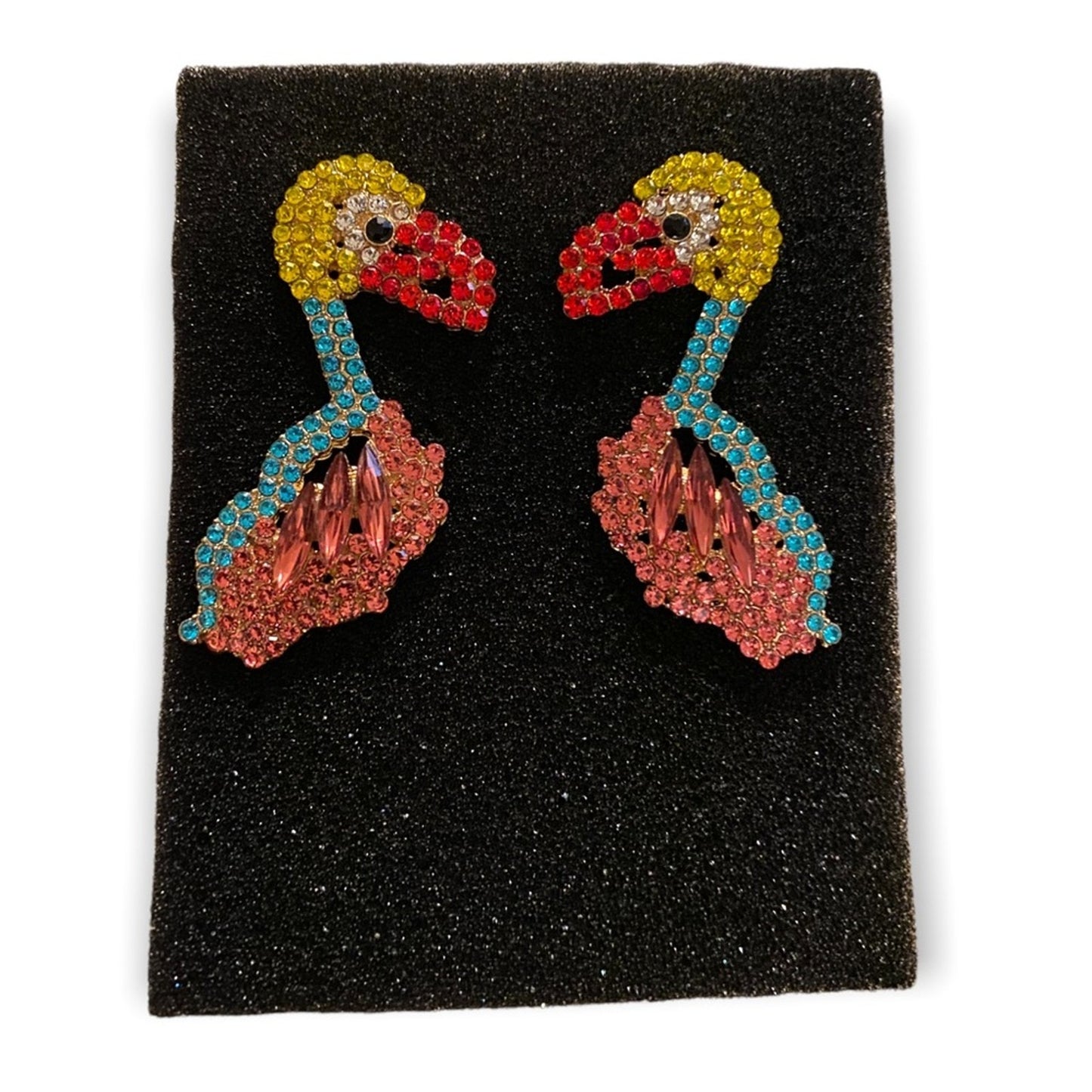 Colorful bird earrings on a black foam on a white background
