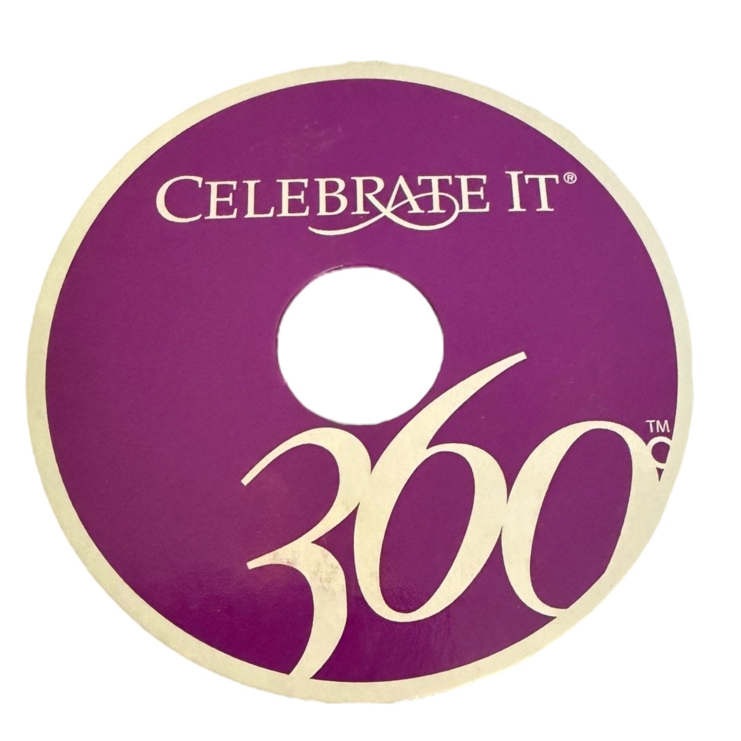 A circular purple disc with a cream-colored border, featuring the text 'CELEBRATE IT 360' in cream lettering, shown on a plain white background.