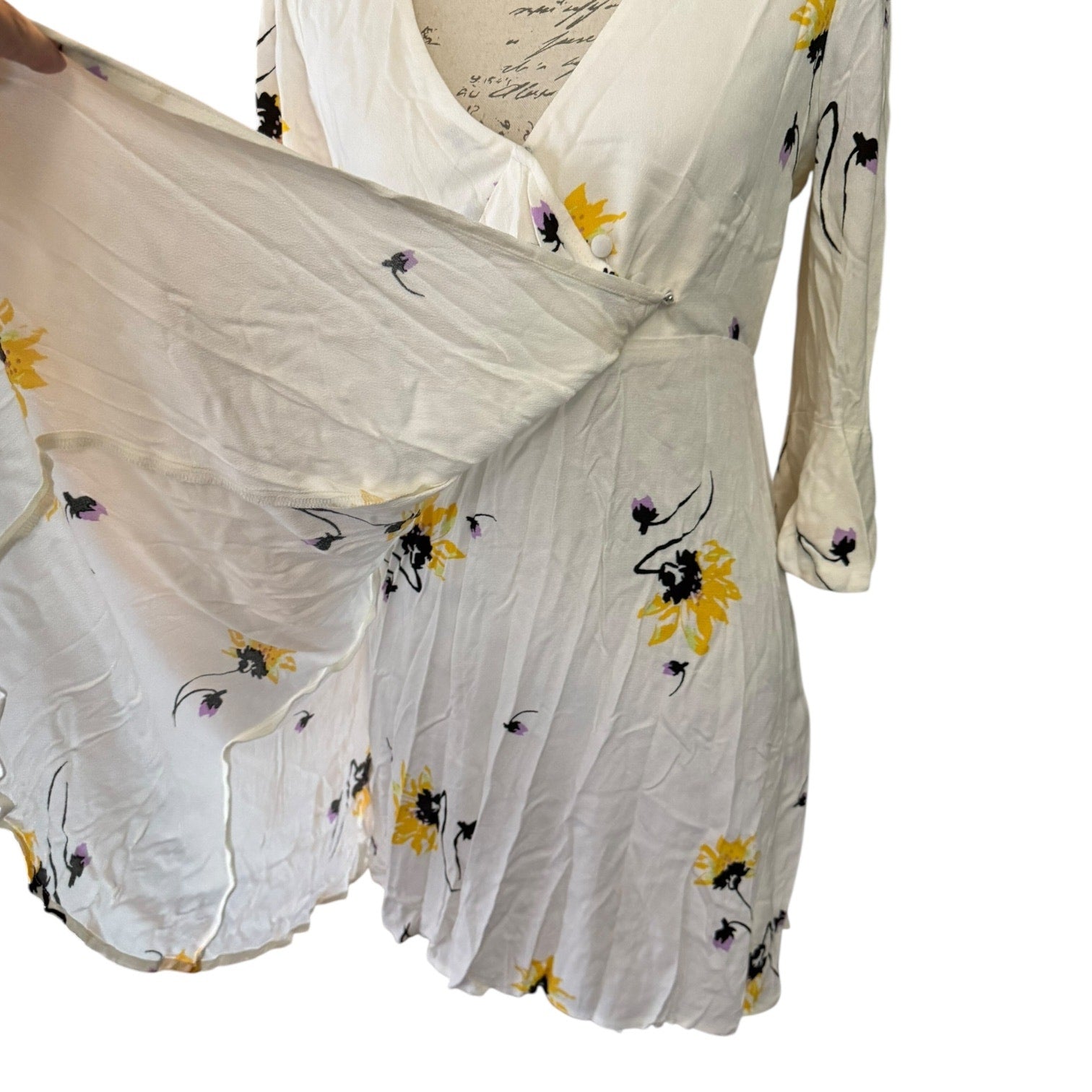 off White dress with floral patterns held up against a white background