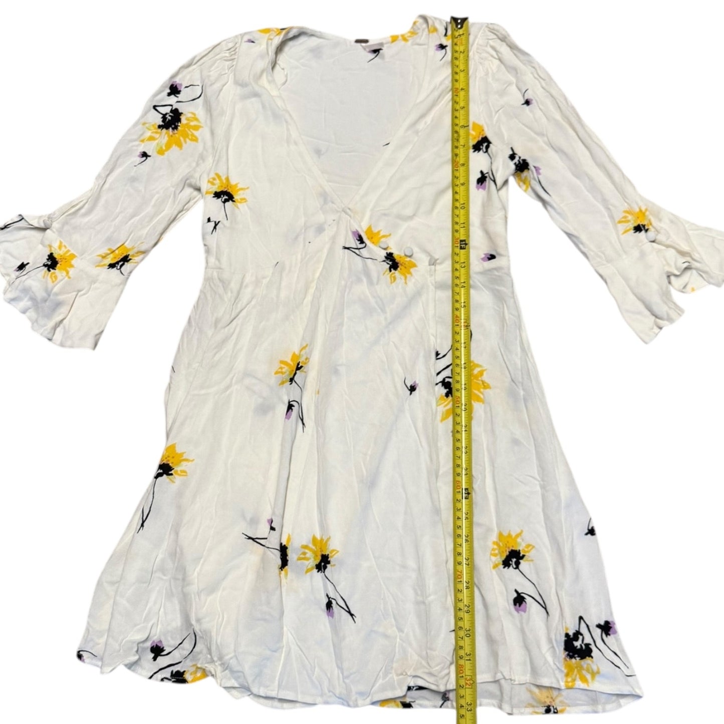 Off White dress with floral patterns and a measuring tape for size reference on a white background