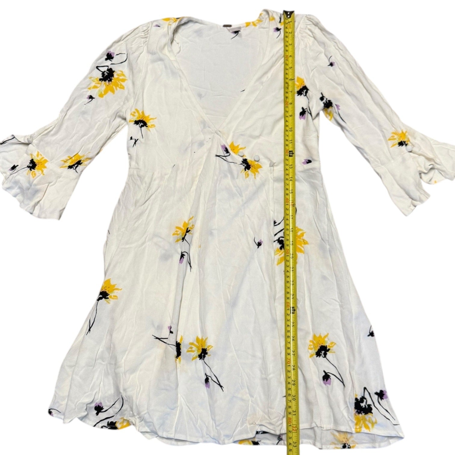 Off White dress with floral patterns and a measuring tape for size reference on a white background