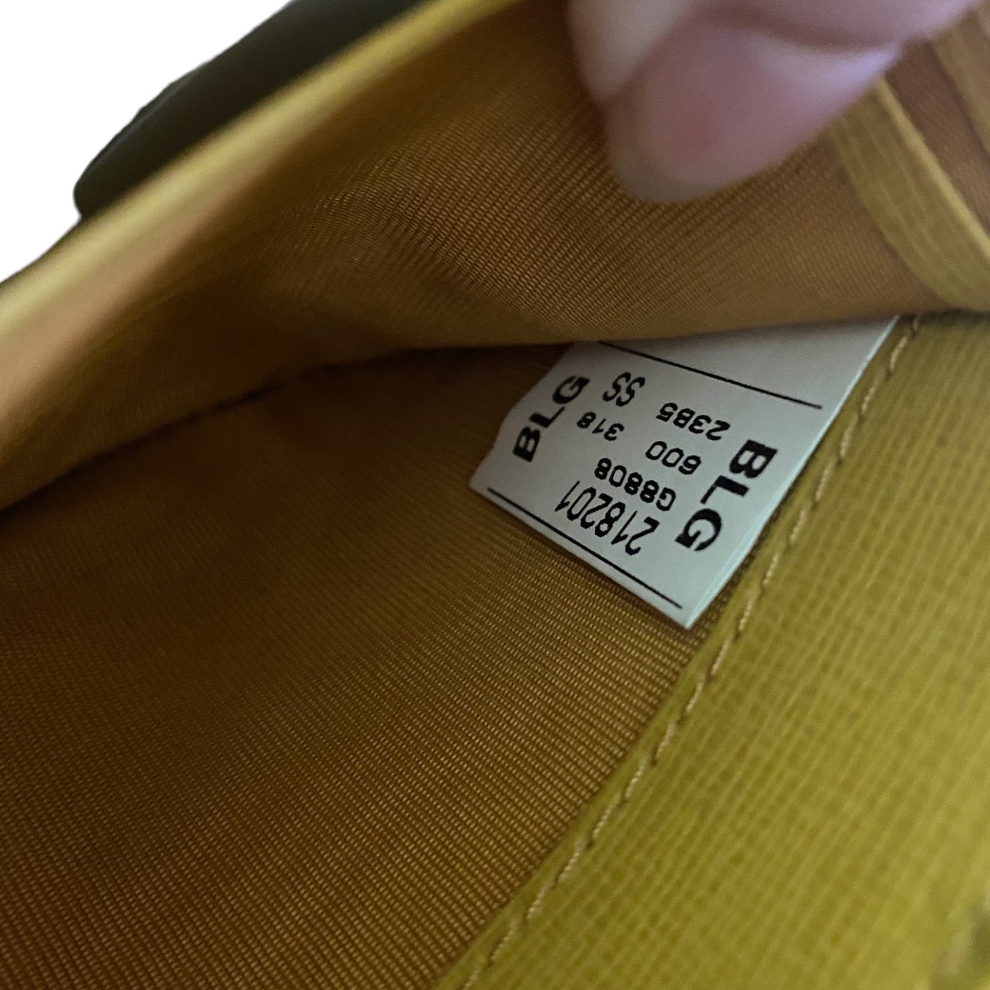 Close-up of the interior lining of a yellow wallet, showing a sewn-on size and model label .